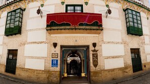 Een historisch gebouw met een rood luifel, een bord waarop hotel staat en een grote bogenpoort.