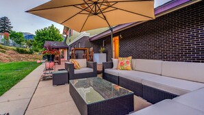 An outdoor patio with wicker furniture, a glass-top table, and a large umbrella. - INNhale Resort and Spa (Manitou Springs)