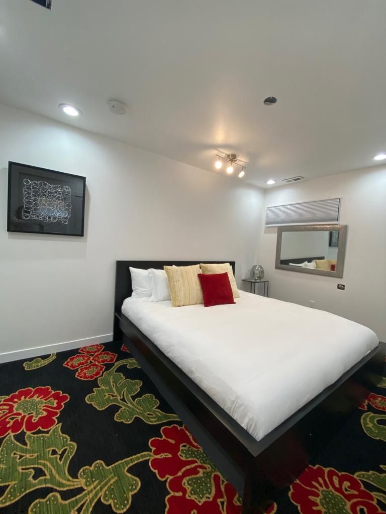 Une chambre d’hôtel avec un lit, un miroir fixé au mur et une œuvre d’art encadrée.