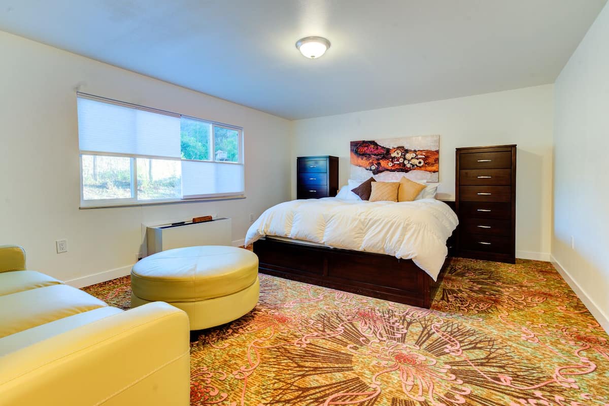 Un dormitorio con cama, cómoda, silla, ventana y radiador.