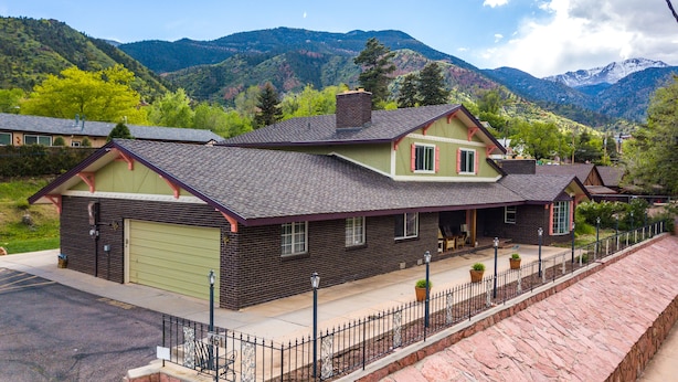 A two-story house with a garage, a covered porch, and a mountain backdrop. - INNhale Resort and Spa (Manitou Springs)