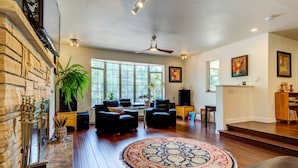 A spacious living room with a fireplace, large windows, and a round rug. - INNhale Resort and Spa (Manitou Springs)