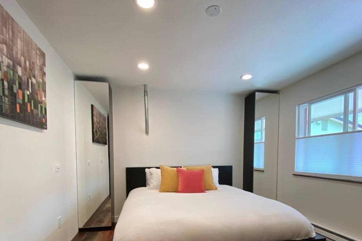 Un dormitorio moderno con una cama grande, una alfombra colorida y una ventana con persianas.