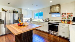 A modern kitchen with stainless steel appliances, a wooden island, and a large window providing natural light. - INNhale Resort and Spa (Manitou Springs)