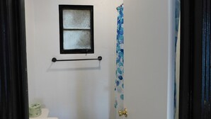 A bathroom with a window, a towel rack, and a shower curtain. - Spruce Pine Inn (Spruce Pine)