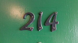 A green wall with the numbers "214" in a decorative metal style. - Spruce Pine Inn (Spruce Pine)