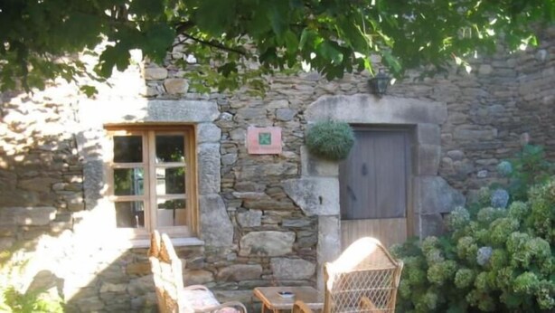 A stone building with a wooden door, a window, and a small table with chairs. - Casa Pousadoira (Mino)
