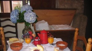 A breakfast table with bread, fruit, juice, and a teapot. - Casa Pousadoira (Mino)