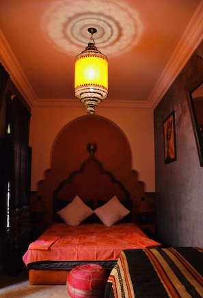 A room with a bed, a chandelier, and a patterned rug.