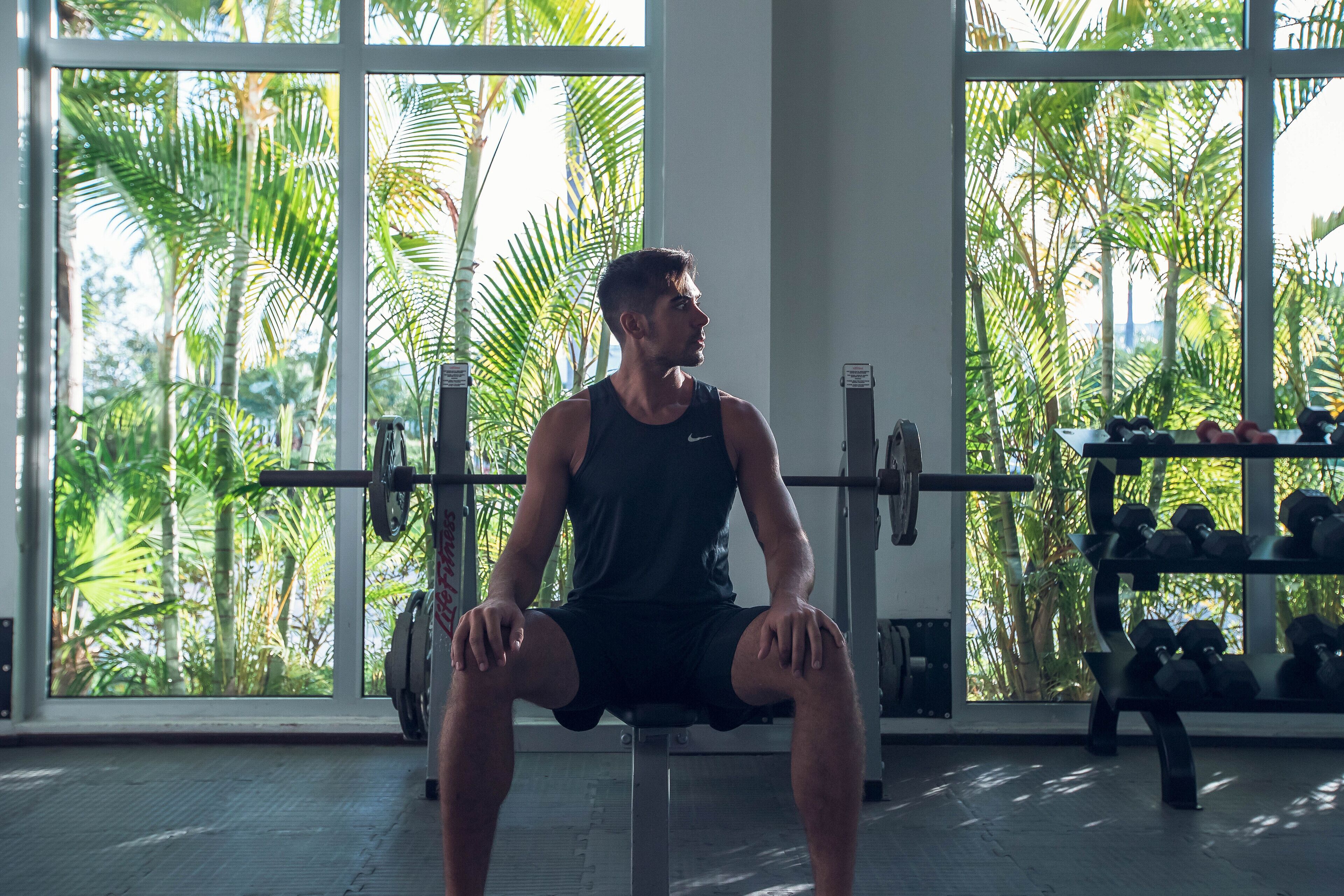 Une salle de sport avec de grandes fenêtres, un banc et des poids.