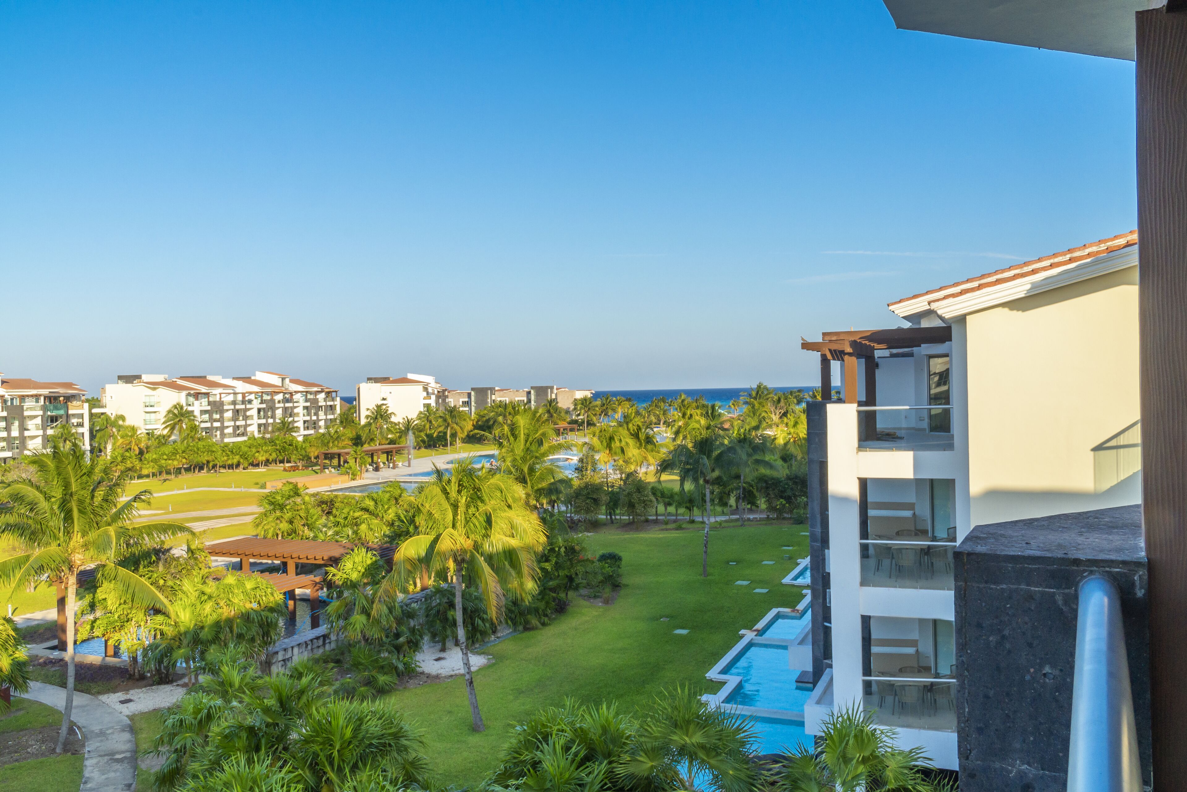 A resort with multiple buildings, a swimming pool, and palm trees.