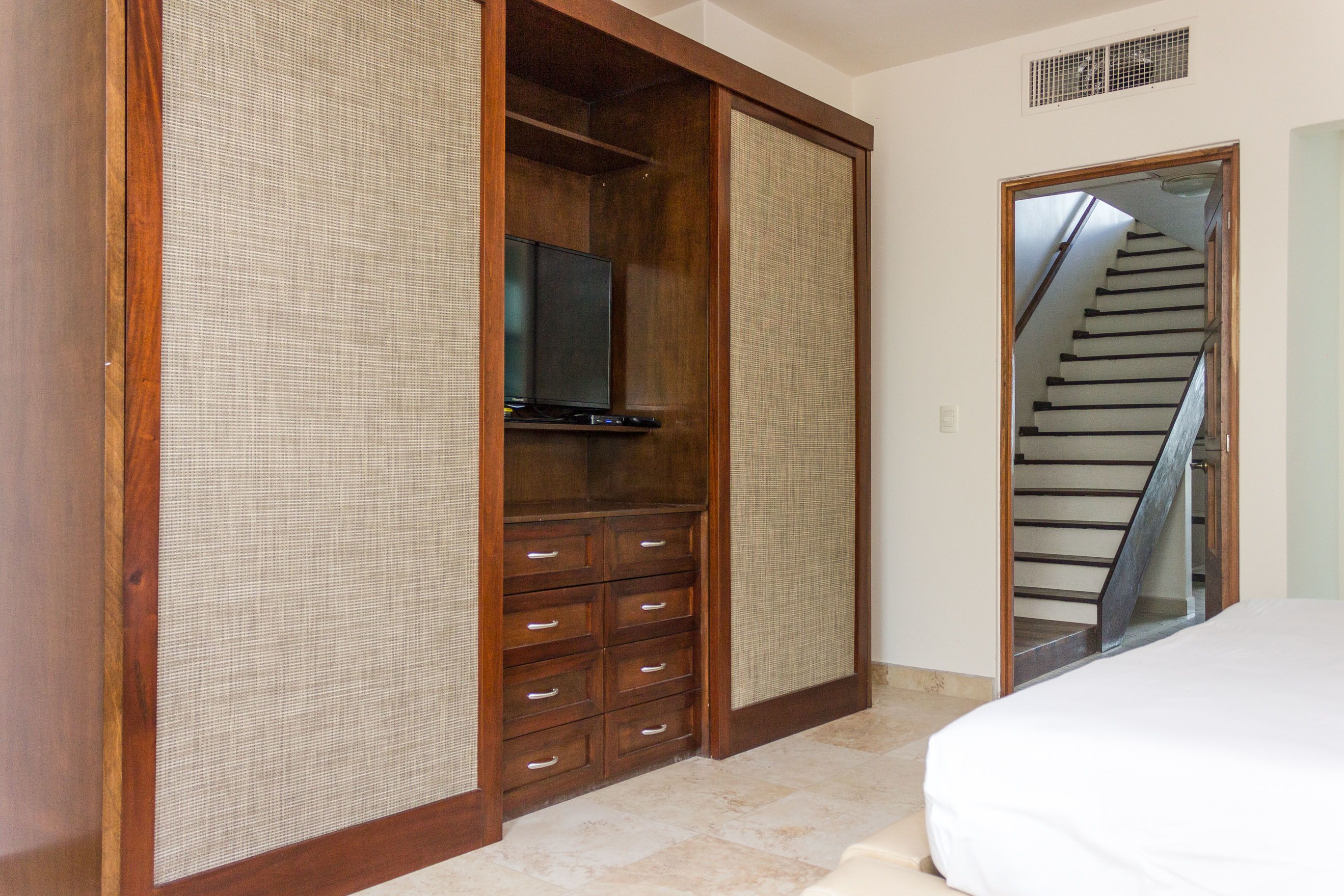 A bedroom with a large wardrobe, a television, and a staircase.