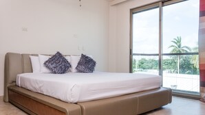 A bedroom with a large bed, a view of the outdoors through a sliding glass door, and a modern design. - Mimosa Penthouse 2 by Realty Group (Playa del Carmen)