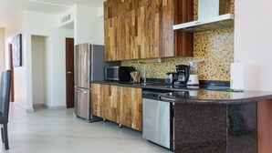 A modern kitchen with wooden cabinets, stainless steel appliances, and a colorful backsplash. - Mimosa Penthouse 2 by Realty Group (Playa del Carmen)