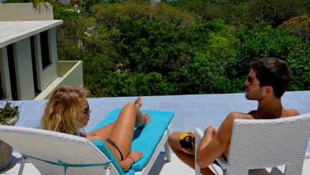 Two people relaxing on sun loungers with a view of the ocean and greenery in the background. - Mimosa Penthouse 2 by Realty Group (Playa del Carmen)