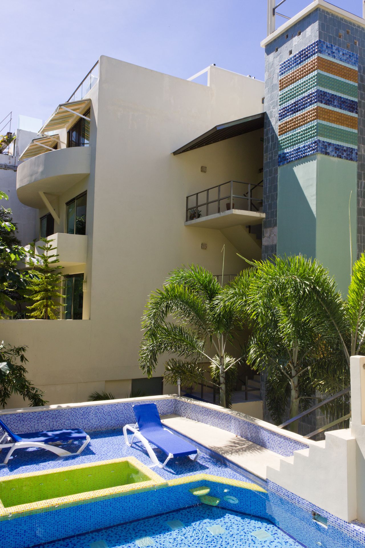 Un edificio moderno con area piscina, comprensiva di piscina con piastrelle blu e lettini.
