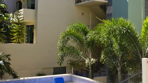 A modern building with a pool area, including a blue-tiled pool and lounge chairs. - Mimosa Flat by Realty Group (Playa del Carmen)