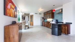 A modern kitchen with wooden cabinets, a black island, and a red pendant light. - Mimosa Flat by Realty Group (Playa del Carmen)