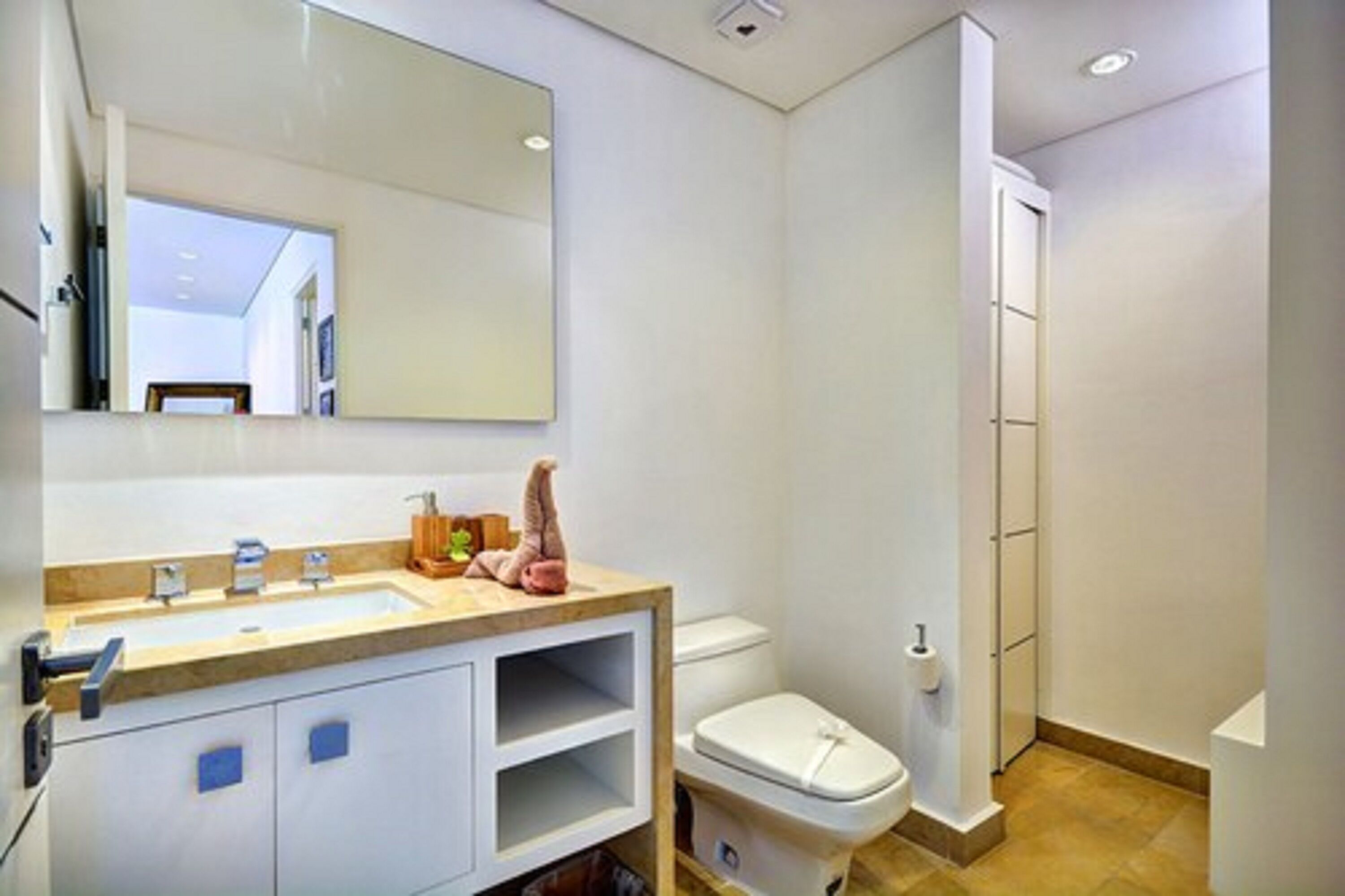 A modern bathroom with a large mirror, a sink with a wooden countertop, and a toilet.