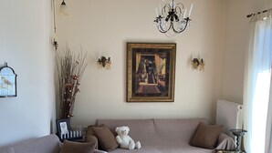 A living room with a beige sofa, a small table with candles, a teddy bear, and a framed picture on the wall. - Arahova Cozy Apartment (Distomo-Arachova-Antikyra)