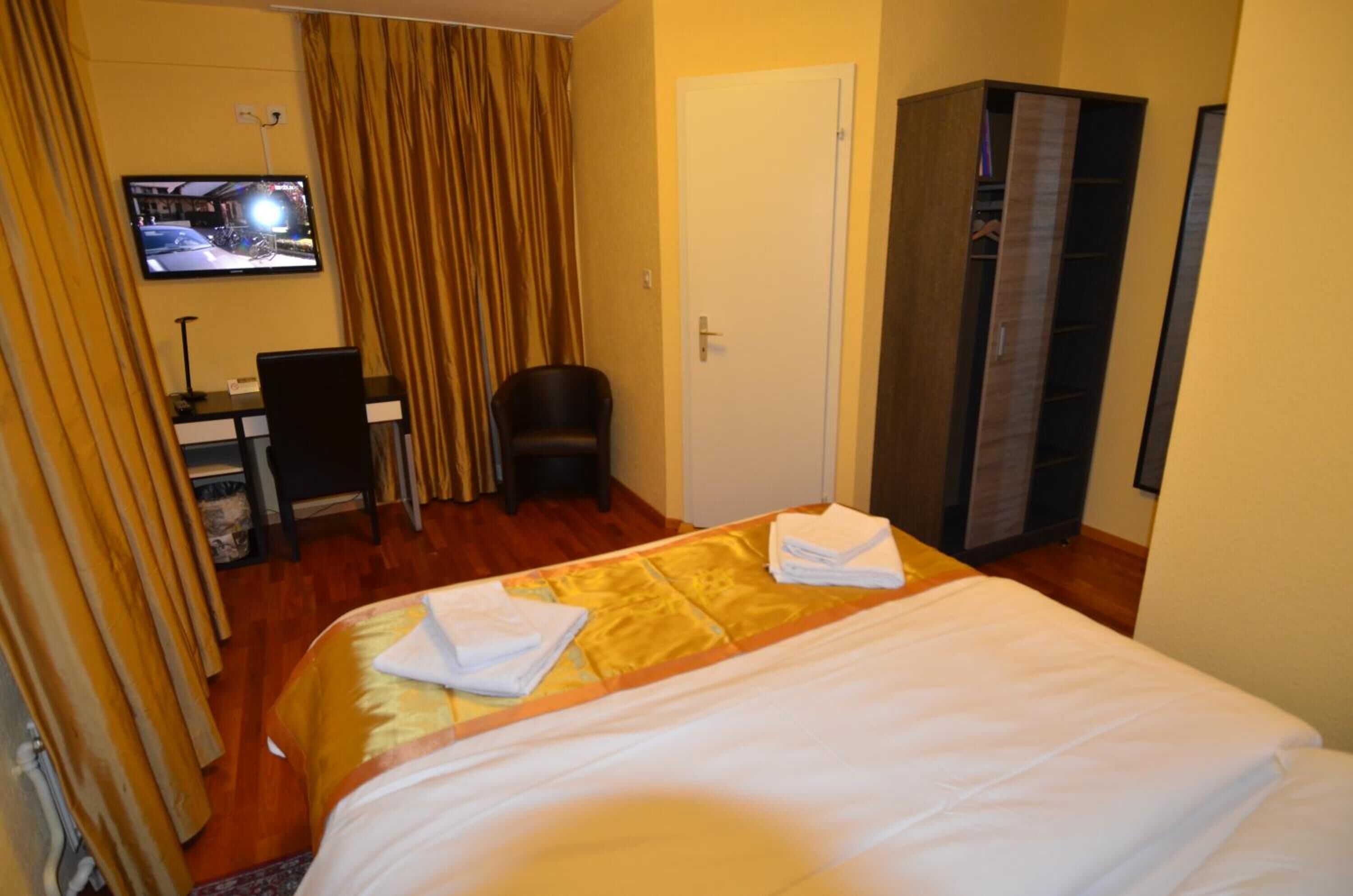 Een hotelkamer met een bed, een bureau, een stoel, een televisie en een kledingkast.