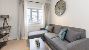 Un salon moderne avec un canapé gris, une table basse et une horloge murale.