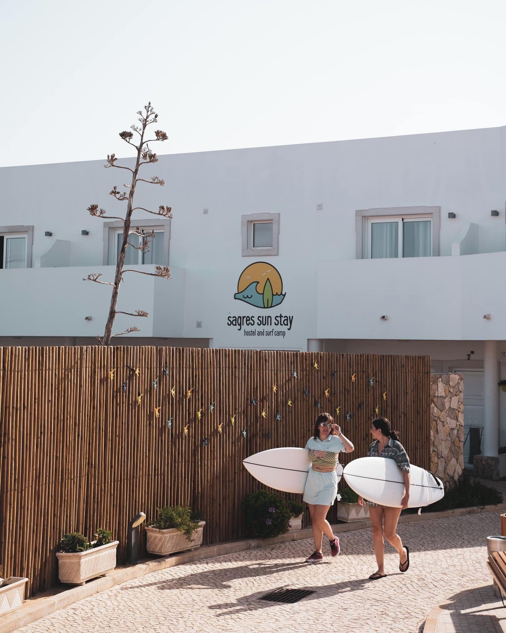 Ein Hostel mit einem Schild mit der Aufschrift 'Sagas Sun Stay' und einem Holzzaun mit Blumentöpfen.