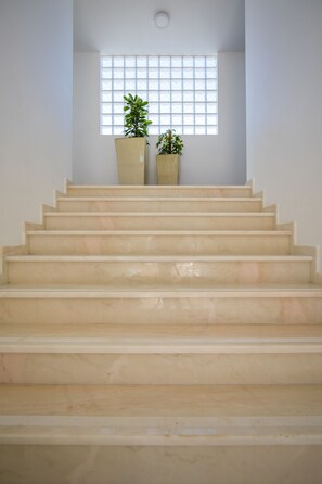 A staircase with a handrail, leading to a landing with a window and two potted plants. - Sagres Sun Stay - Surf Camp & Hostel (Vila do Bispo)
