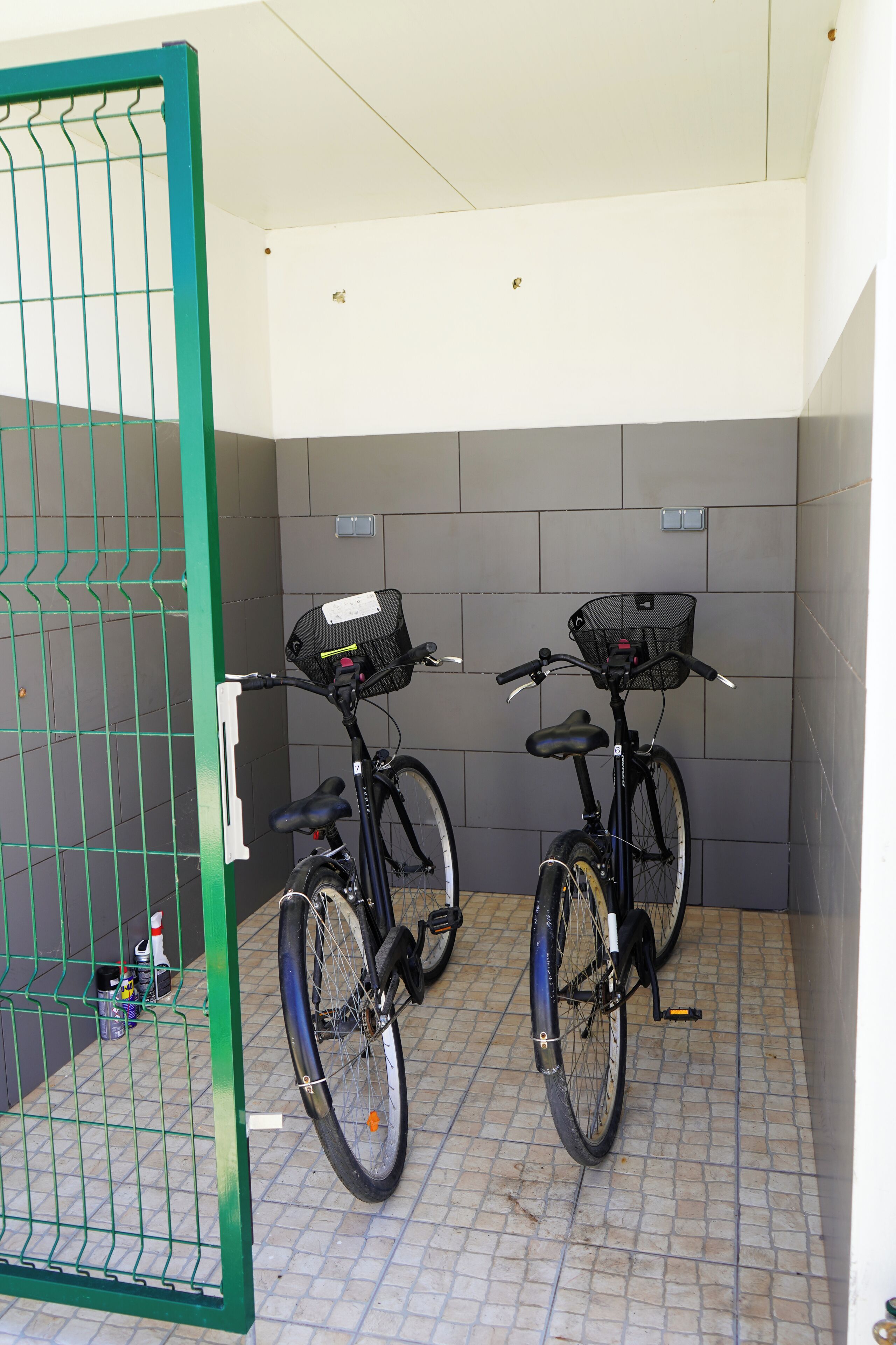 Un espace de stockage pour vélos où deux vélos sont fixés à un support métallique vert.