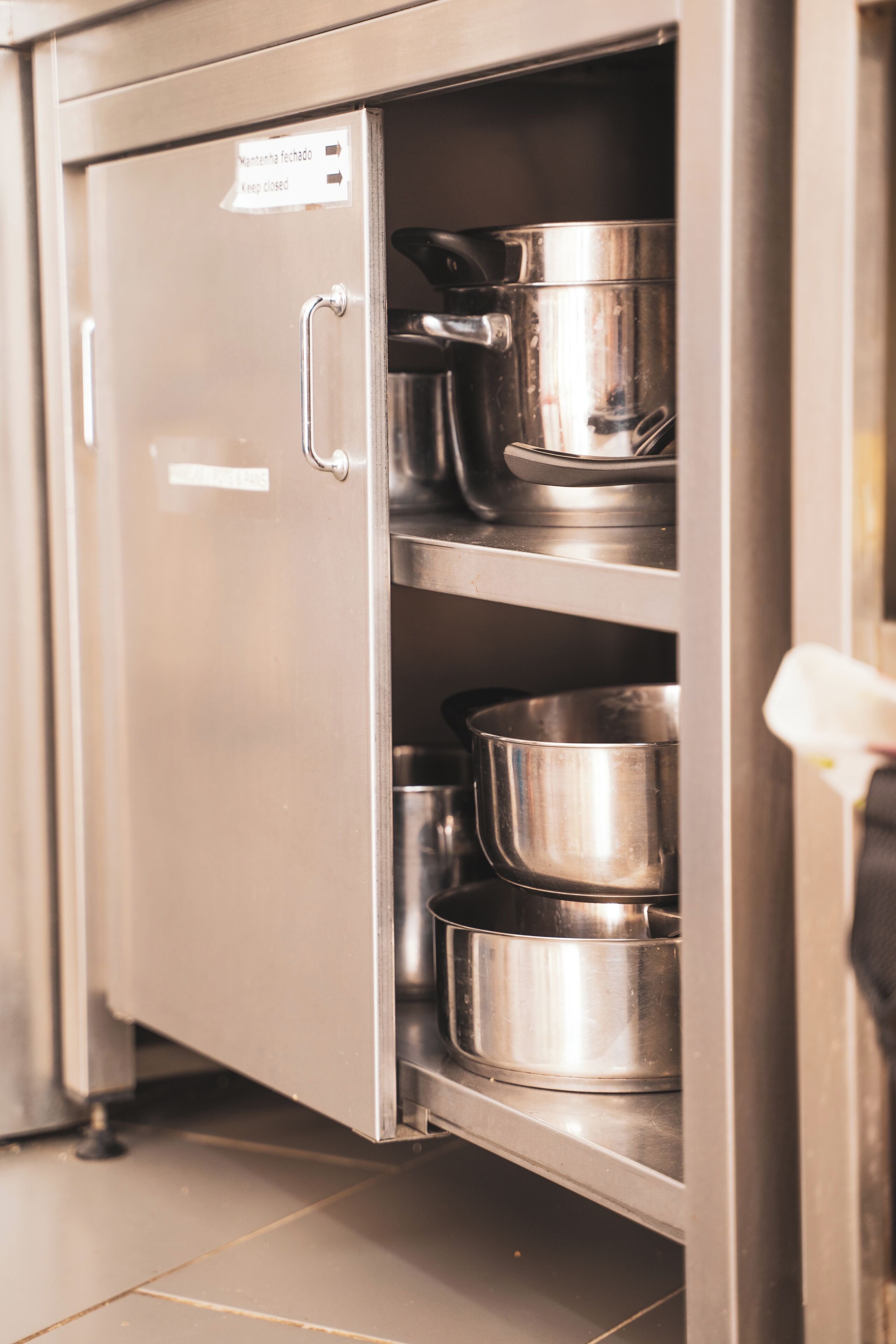 A stainless steel kitchen cabinet with a sign indicating it should be kept closed.