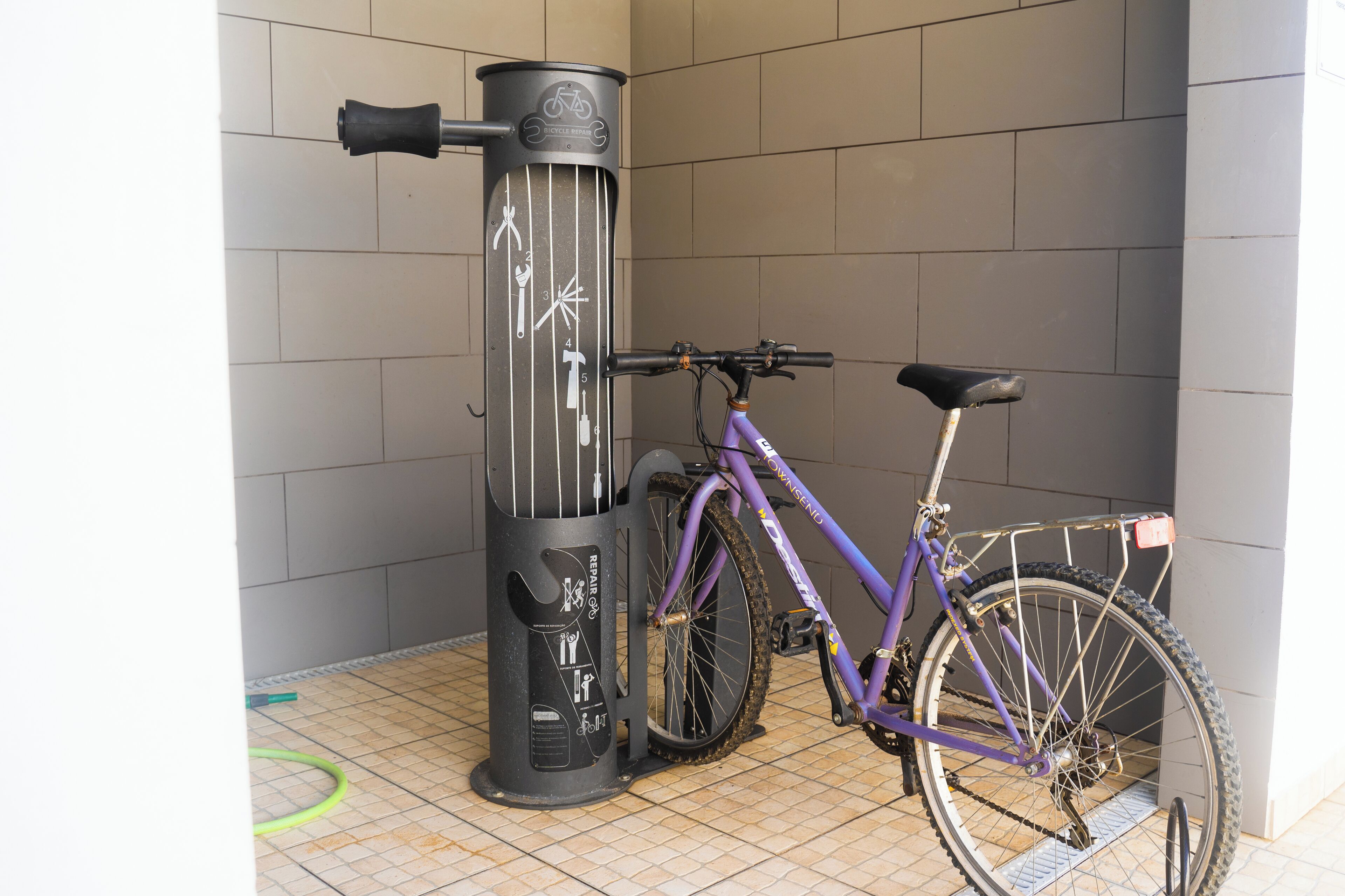 A bicycle parked next to a black vertical object with a bicycle symbol and arrows, possibly a bike rack or charging station.