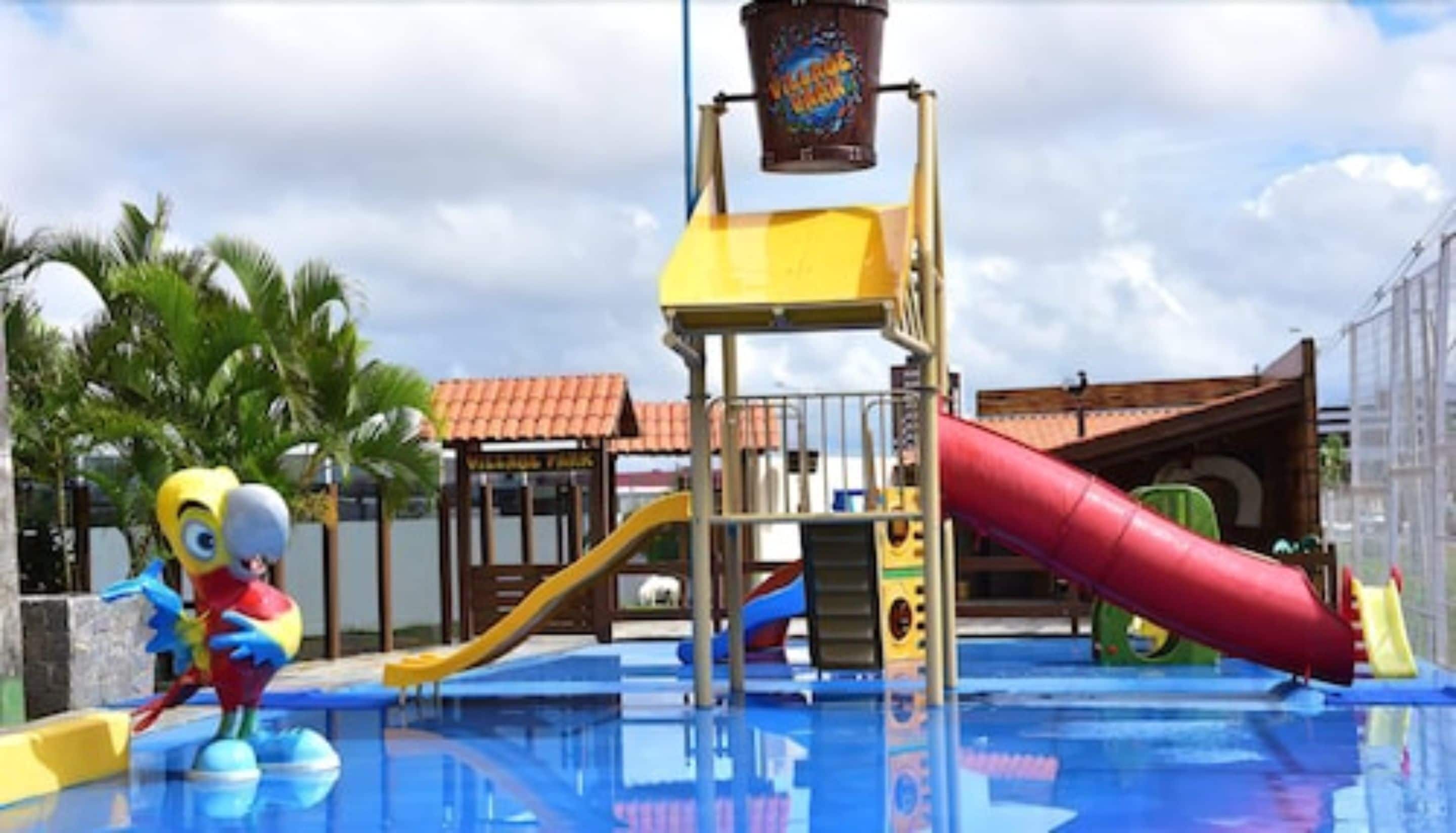Ein Wasserpark mit einer gelb-roten Rutsche, einem Minion-Maskottchen und einem Schwimmbecken.