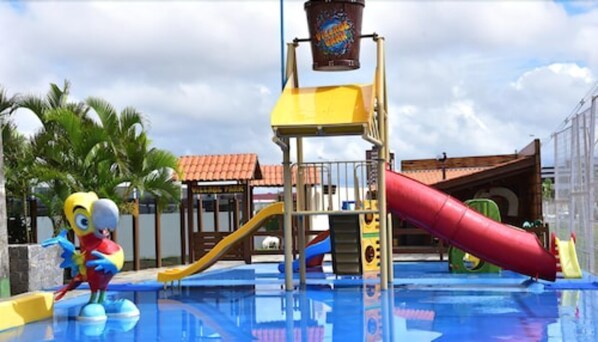 A water park with a yellow and red slide, a minion mascot, and a pool.