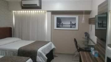 Habitación de hotel con dos camas, un escritorio con silla, televisor y un cuadro en la pared.