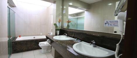 A modern bathroom with two sinks, a toilet, and a glass shower enclosure.