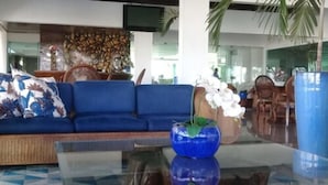 A modern living room with a blue sofa, a glass coffee table, and a decorative vase.