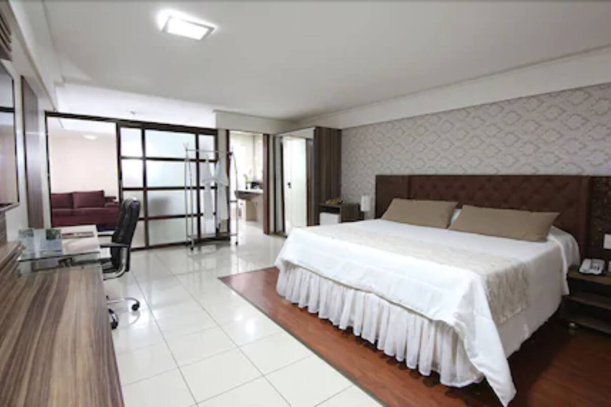 Une chambre d’hôtel moderne, dotée d’un grand lit, d’un bureau et d’une chaise. Une porte coulissante donne accès à un balcon.