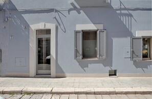Un edificio con una puerta y dos ventanas con contraventanas.
