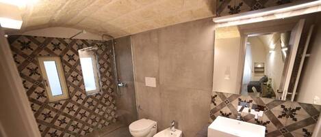 A bathroom with a shower, toilet, bidet, and sink.