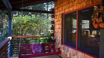A wooden deck with a red bench and a hanging swing.