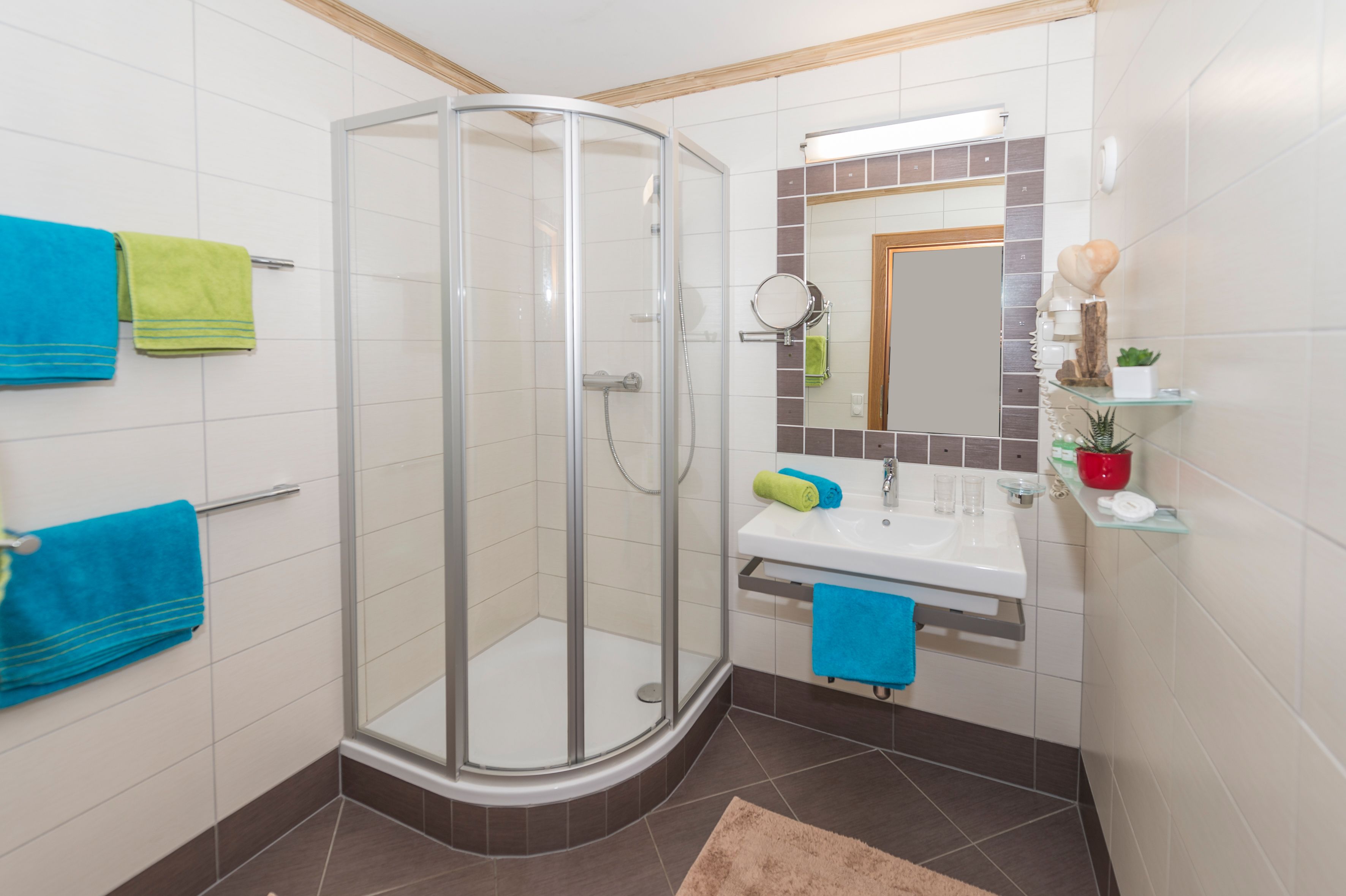 Un baño moderno con cabina de ducha de vidrio, lavamanos con espejo y repisa con artículos de aseo.