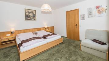 A neatly arranged bedroom with a wooden bed, bedside tables, a chair, and a door.