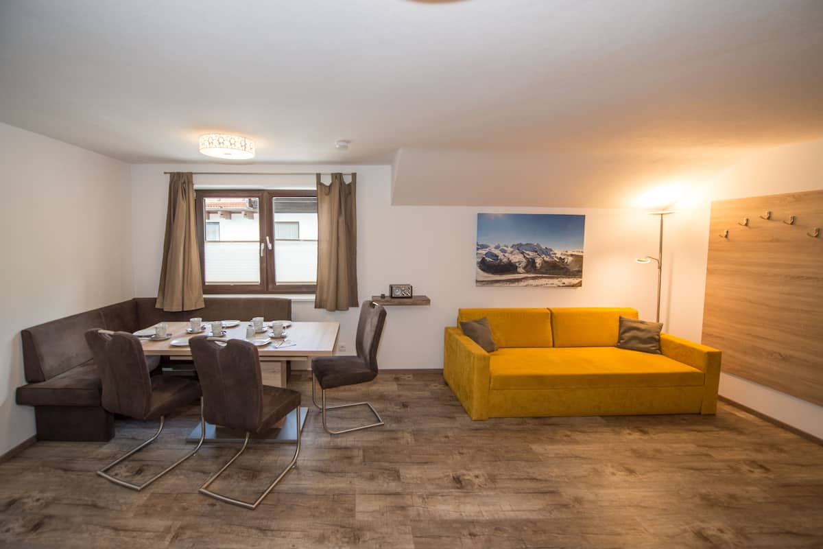 A dining area with a table, chairs, and a yellow sofa.