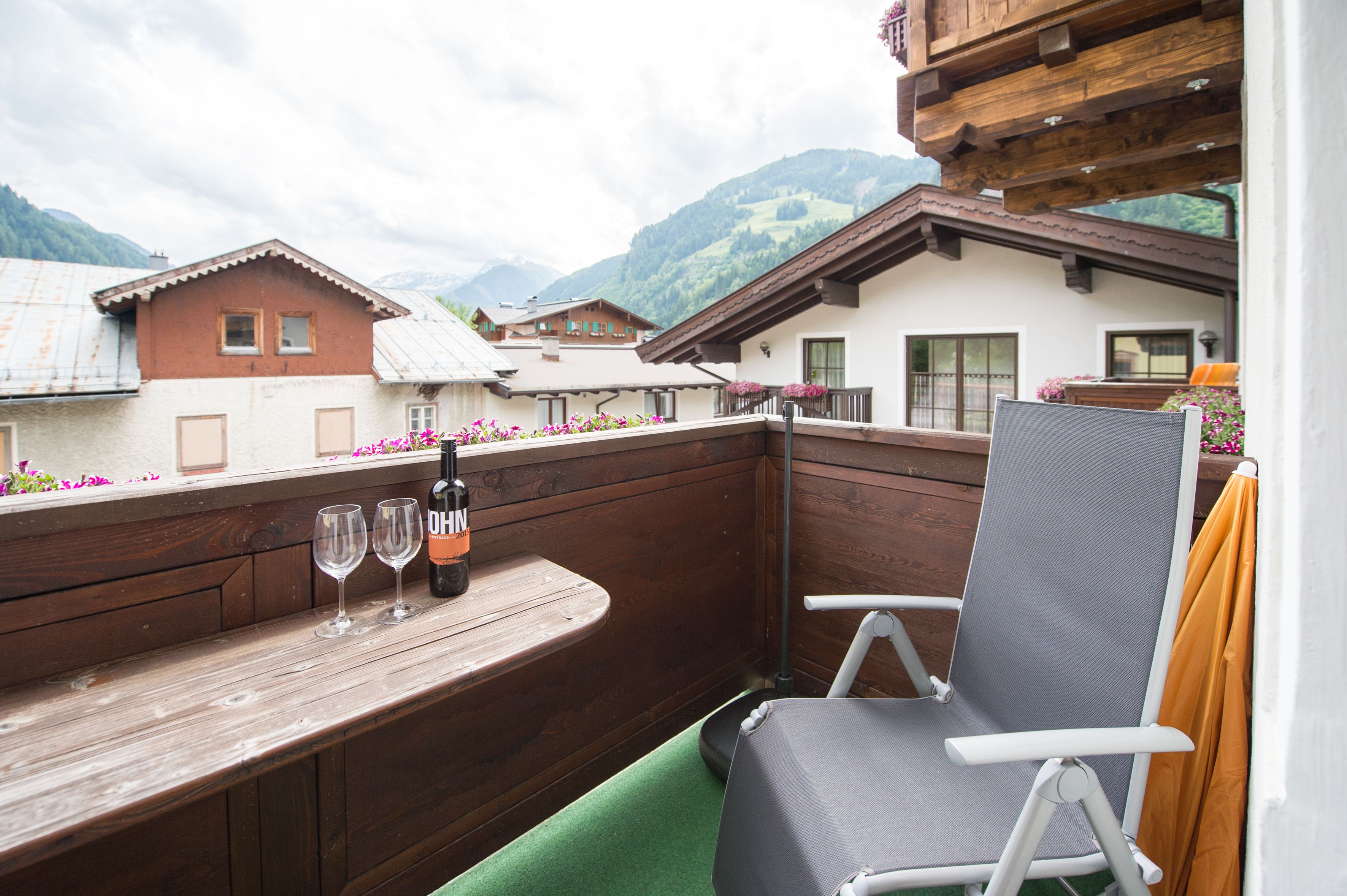 Una terraza de madera con una mesa, dos copas de vino y una botella.