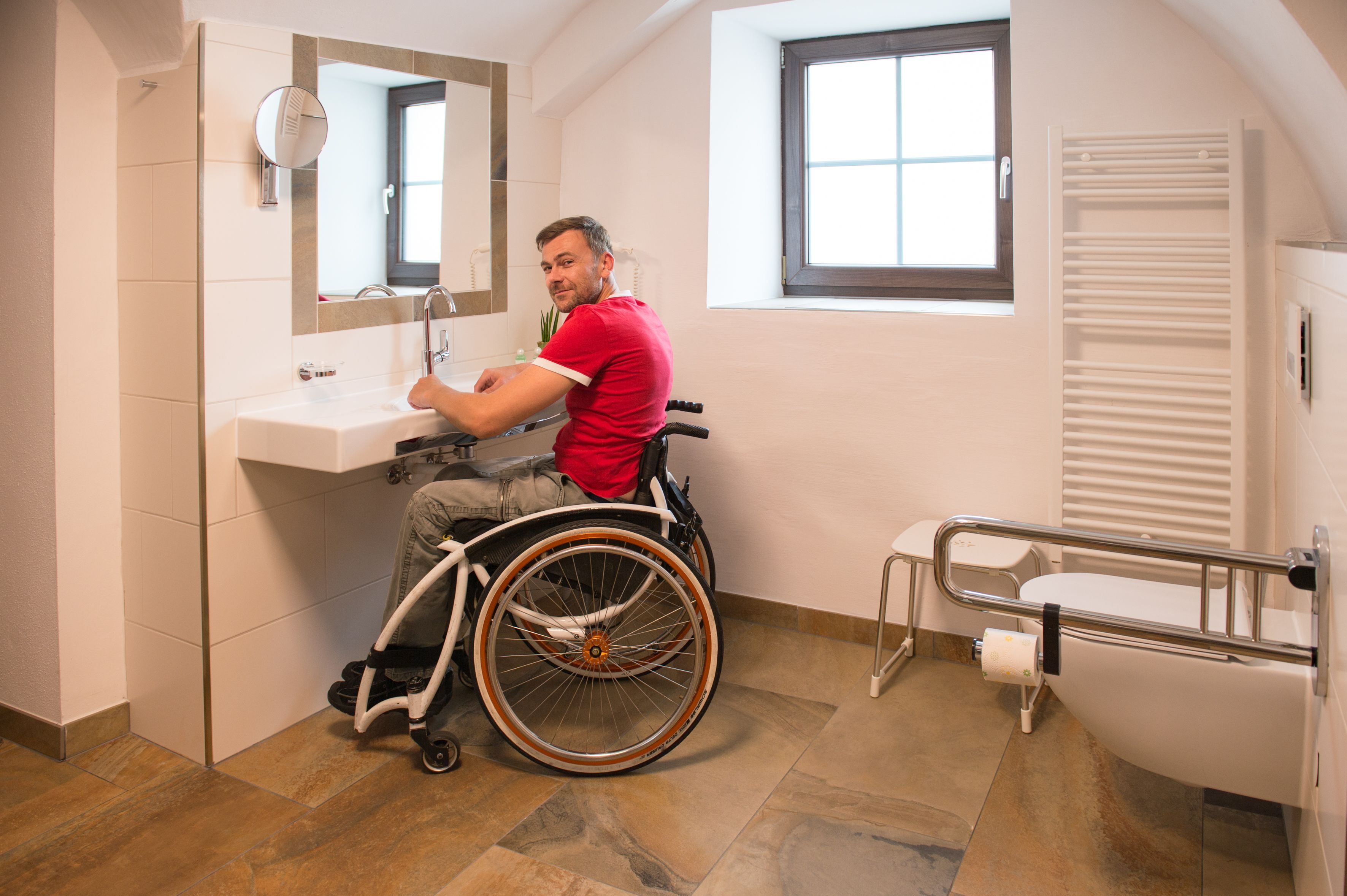 A wheelchair-accessible bathroom with a sink, mirror, and hand dryer.