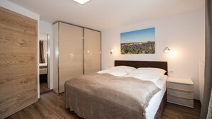 Un dormitorio con cama, mesita de noche y un cuadro de un paisaje.