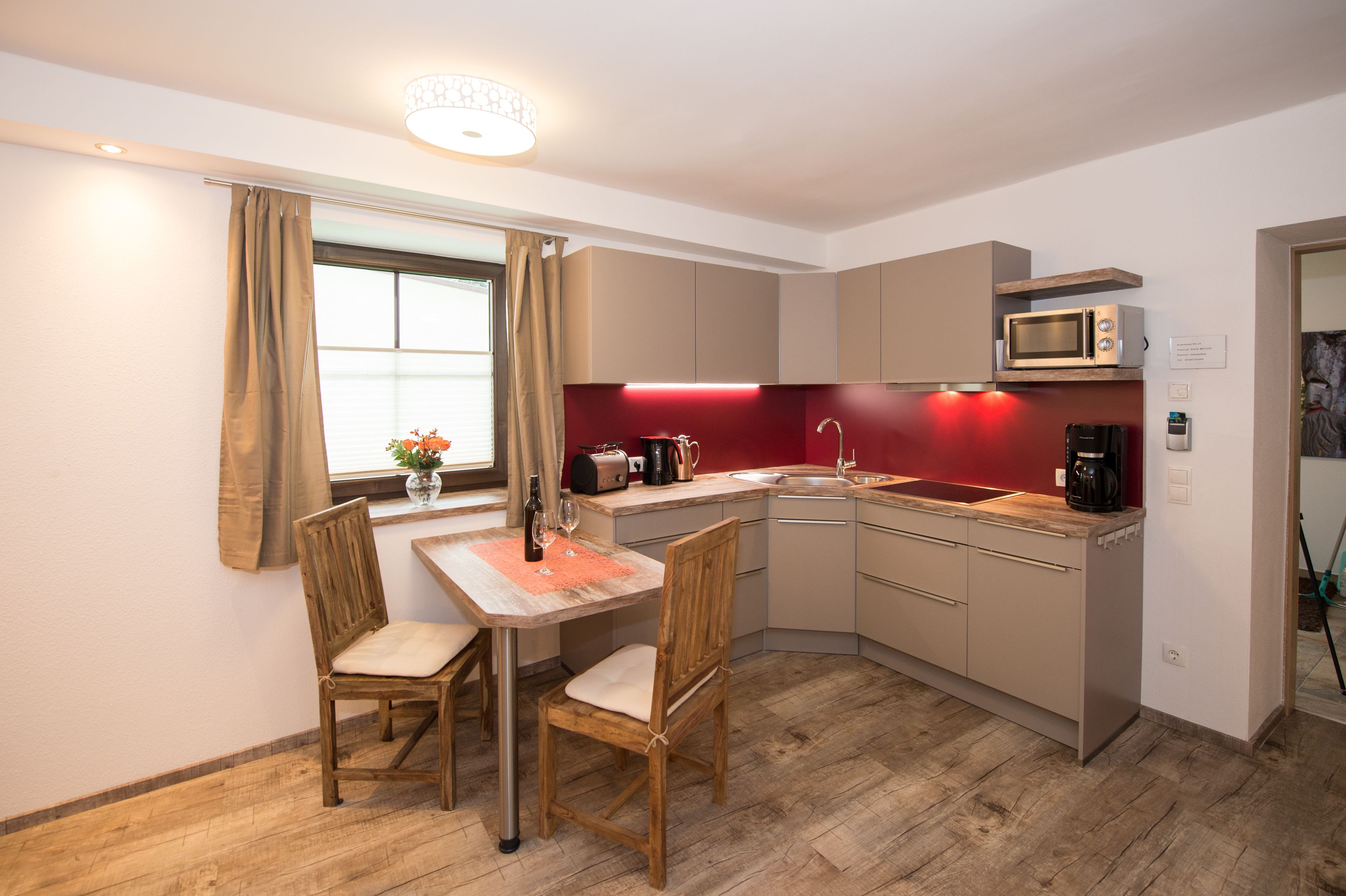 Cocina compacta con comedor, que incluye una mesa, sillas, un microondas y un lavamanos.