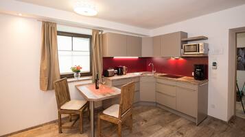 Cocina compacta con comedor, que incluye una mesa, sillas, un microondas y un lavamanos.