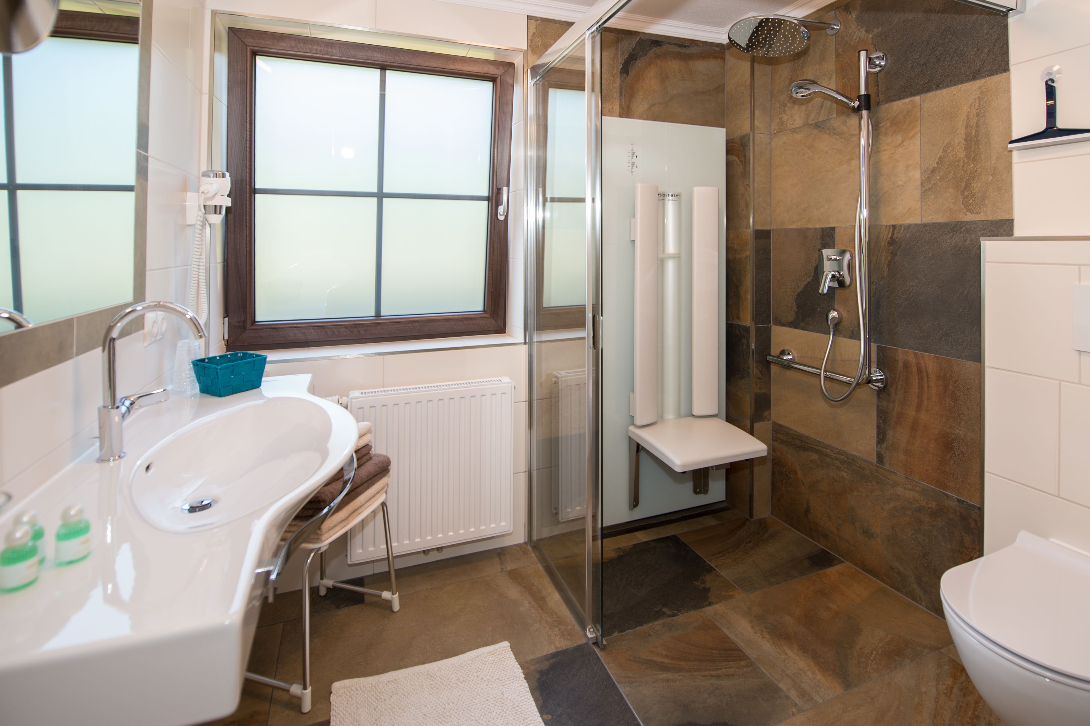 A modern bathroom with a glass-enclosed shower, a freestanding bathtub, and a toilet.