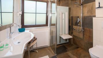 A modern bathroom with a glass-enclosed shower, a freestanding bathtub, and a toilet.